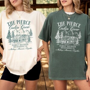 Pu&ograve; includere: Due magliette a maniche corte, una color crema e una verde, con la scritta "THE PIERCE Cabin Crew" sopra una grafica di una baita e montagne. Il testo "FAMILY REUNION BRECKENRIDGE, CO Making Memories Together" &egrave; sotto.