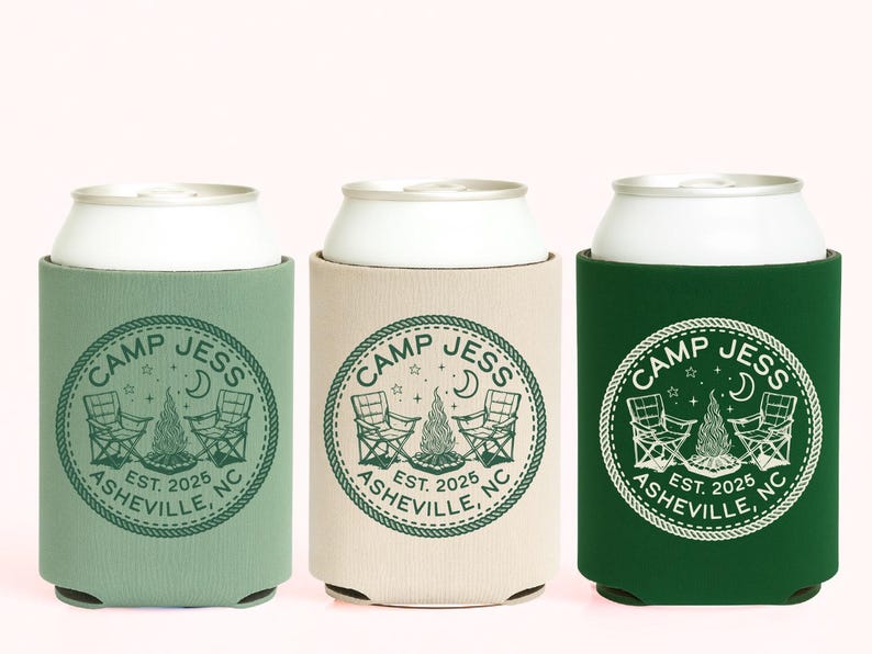 May include: Three cylindrical foam can coolers in sage green, beige, and dark forest green. Each features a circular graphic with the text CAMP JESS, ASHEVILLE, NC, EST. 2025, surrounding an illustration of two folding chairs and a campfire.