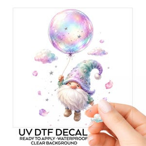 May include: A UV DTF decal featuring a gnome with a long white beard wearing a pastel-colored hat adorned with silver stars. The gnome holds a large, iridescent, semi-transparent balloon surrounded by small clouds and floating petals.