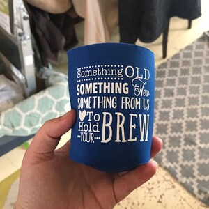 May include: Blue can cooler with white text that reads "Something Old, Something New, Something From Us, To Hold Your Brew".