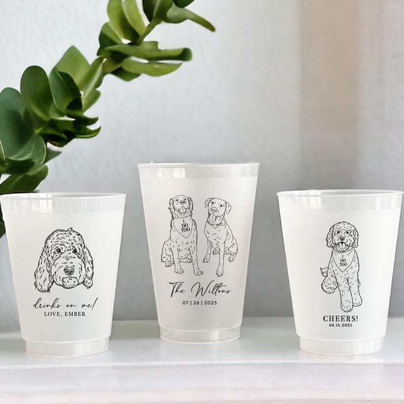 May include: Three frosted plastic cups with black line drawings of dogs. One cup has a doodle dog with "drinks on me!" and "LOVE, EMBER". Another has two dogs with "I DO TOO" and "The Willtons 07|26|2025". The last cup has a doodle dog with "CHEERS! 08.16.2025".