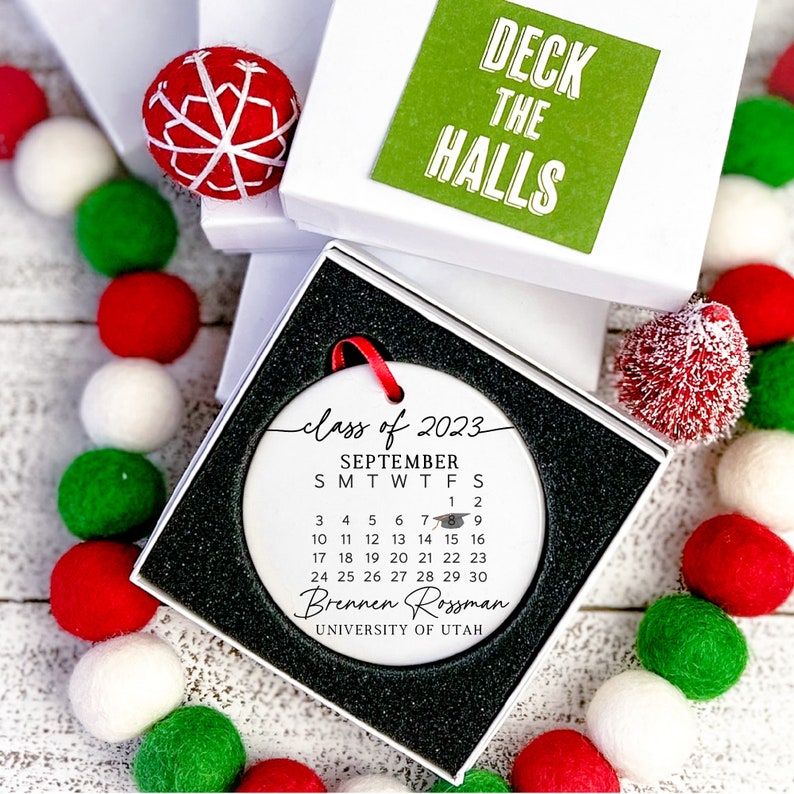 May include: White ceramic bauble with a black and white calendar for September 2023, the text "class of 2023", and the name "Brennen Rossman" with the text "UNIVERSITY OF UTAH" below.