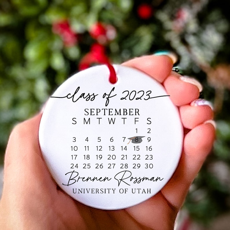 May include: White ceramic bauble with the text "class of 2023" and a calendar for September with a graduation cap icon on the 8th. The text "Brennen Rossman" and "UNIVERSITY OF UTAH" are also included.