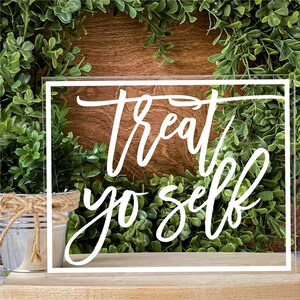 May include: White acrylic sign with a white border and the text "treat yo self" in a handwritten font.