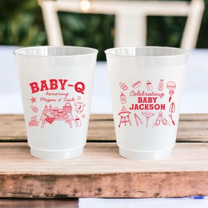 Puede incluir: Dos vasos de pl&aacute;stico blanco con dise&ntilde;os rojos. Un vaso dice "BABY-Q en honor a Megan + Zach" con una escena de picnic. El otro vaso dice "Celebrando BABY JACKSON" con un tema de barbacoa.