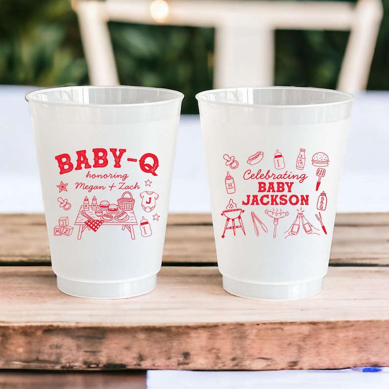Puede incluir: Dos vasos de pl&aacute;stico blanco con dise&ntilde;os rojos. Un vaso dice "BABY-Q en honor a Megan + Zach" con una escena de picnic. El otro vaso dice "Celebrando BABY JACKSON" con un tema de barbacoa.