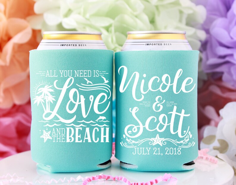 May include: Two turquoise blue can coolers with white text. One cooler says "All you need is Love and the Beach" with a palm tree, starfish, and dolphin graphic. The other cooler says "Nicole & Scott" with a starfish and wave graphic and the date "July 21, 2018".