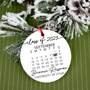 May include: White round bauble with black text that reads "class of 2023", "SEPTEMBER", "SMTWTFS", "1 2", "3 4 5 6 7 8 9", "10 11 12 13 14 15 16", "17 18 19 20 21 22 23", "24 25 26 27 28 29 30", "Brennen Rossman", and "UNIVERSITY OF UTAH".