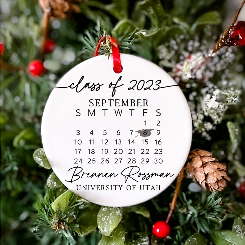 May include: White ceramic bauble with a black calendar for September 2023, featuring the text "class of 2023" and "Brennen Rossman" with the University of Utah logo.