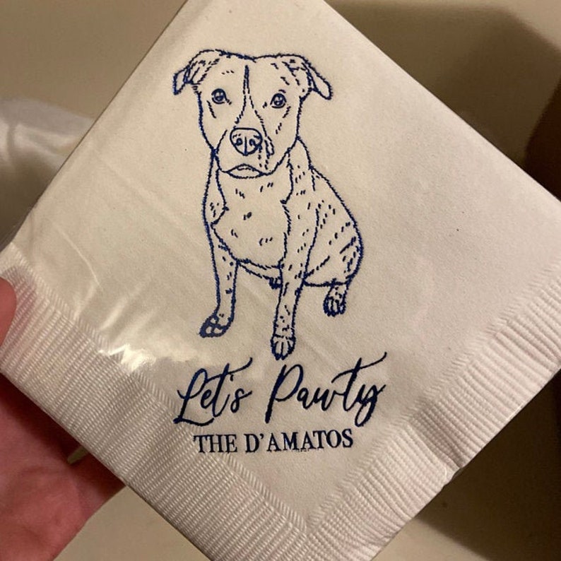 May include: White paper napkin with a blue line drawing of a dog sitting. The text "Let's Pawty" and "The D'Amatos" is printed in blue below the dog.