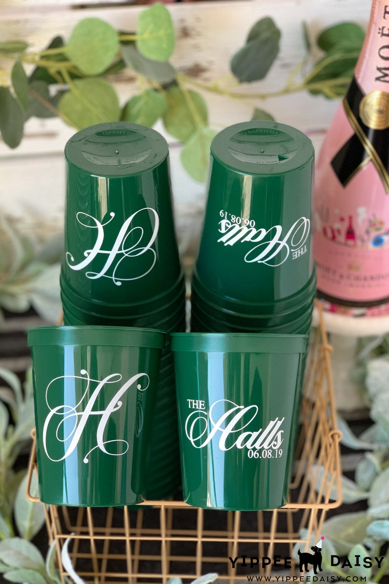 Puede incluir: Pila de vasos de pl&aacute;stico verde con letras blancas. El vaso de arriba dice "The Halls 06.08.19".