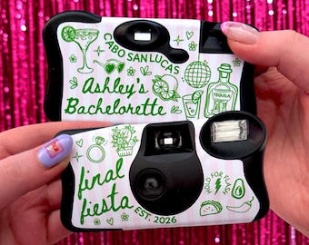 May include: Two disposable cameras with white and light pink striped casings featuring green line art. The top camera reads Cabo San Lucas, Ashley's Bachelorette, and includes icons of a margarita, disco ball, and tequila. The bottom camera reads final fiesta EST. 2026 with icons of a ring, cactus, avocado, and taco.