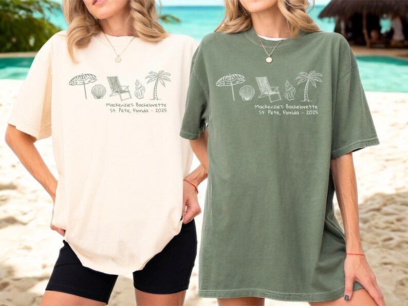 May include: Two oversized t-shirts, one cream and one olive green, with a beach-themed graphic. The graphic includes an umbrella, seashell, beach chair, and palm tree. Text on the shirts reads "Mackenzie's Bachelorette St. Pete, Florida - 2025."
