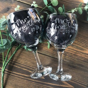 May include: Two clear glass gin glasses with etched designs. The glasses are engraved with "Mr. Geoffrey Clamp 03.04.21" and "Mrs. Geoffrey Clamp 03.04.21".