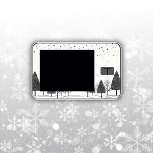 May include: A rectangular, white and silver decorative item with a black screen. The item features a winter forest scene with black trees and falling snow. The background is a gradient of white and silver with snowflake accents.