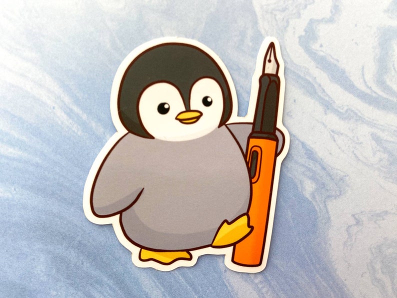 May include: A sticker featuring a cartoon penguin with a gray body, black head, and yellow feet and beak. The penguin is holding an orange and black fountain pen. The sticker is on a light blue background.