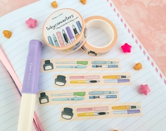 May include: A stationery-themed image featuring washi tape and stickers. The washi tape has a pen design and the stickers feature ink bottles and pens. A purple Pilot Kakuno pen is also visible.