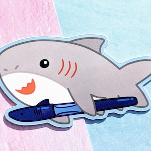 A cartoon shark holding a Jinhao shark fountain pen. The fountain pen has the head and fin of a shark and is made of blue plastic.
