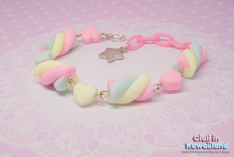 Pode incluir: Um bracelete cor-de-rosa pastel, amarelo e azul com um fecho de estrela e contas em forma de cora&ccedil;&atilde;o. O bracelete &eacute; feito de argila polim&eacute;rica e &eacute; projetado para parecer um marshmallow.