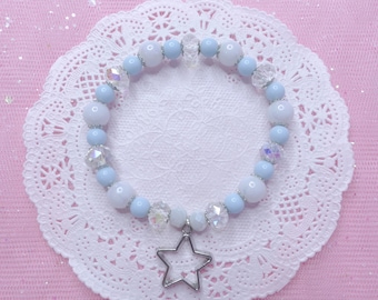 May include: A light blue and white beaded bracelet with a silver star charm. The bracelet is on a white doily.