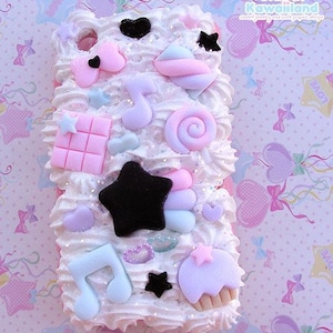 May include: A white phone case decorated with pastel pink, blue, and white 3D candy and star shapes. The case is covered in white frosting and has a glittery finish.