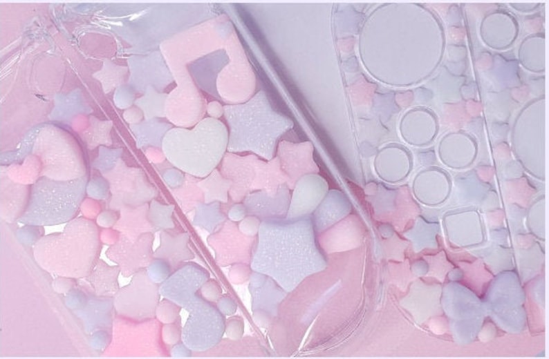 Puede incluir: Una funda de pl&aacute;stico transparente con un dise&ntilde;o rosa y morado. La funda est&aacute; llena de peque&ntilde;as formas de colores pastel, incluyendo estrellas, corazones y notas musicales. La funda est&aacute; dise&ntilde;ada para contener una Nintendo Switch.