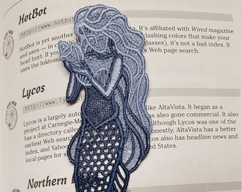 May include: A blue and white embroidered mermaid bookmark with the text "HotBot http://www.hotbot.com" and "Lycos http://www.lycos.com" on the page.