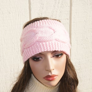 May include: A pink knitted headband with a cable knit pattern.
