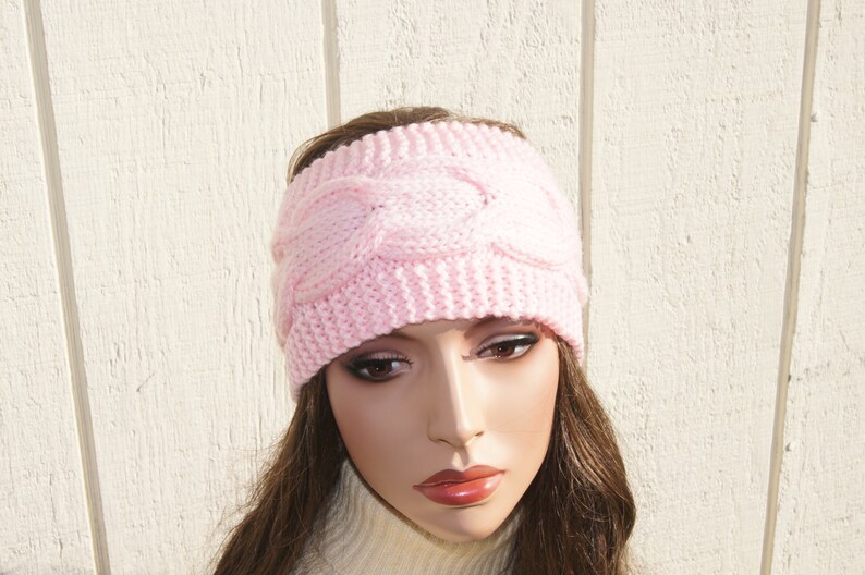 May include: A pink knitted headband with a cable knit pattern.