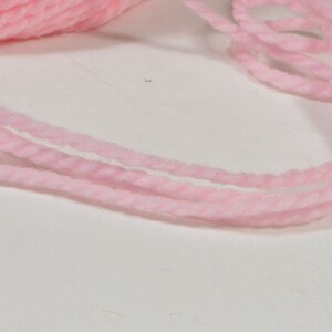 May include: Pink yarn wound into a ball and a loose strand of yarn.