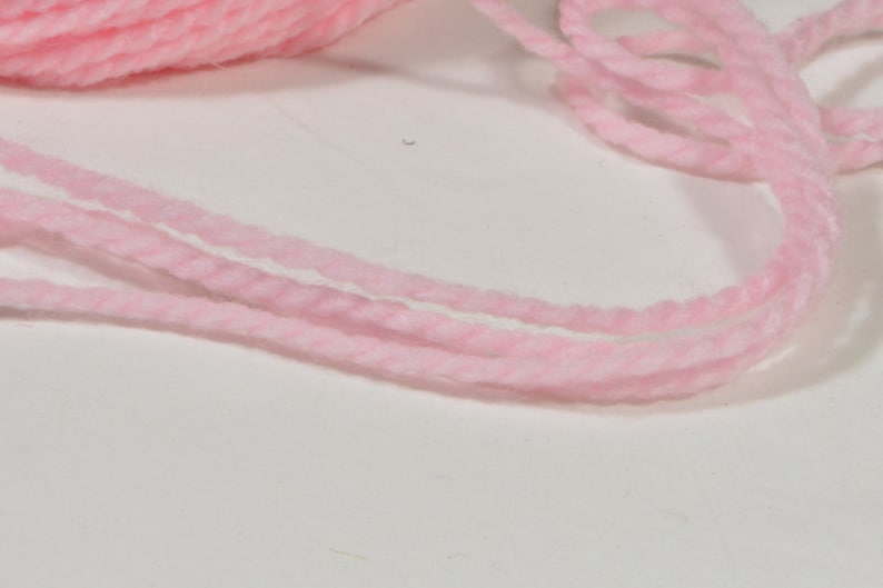 May include: Pink yarn wound into a ball and a loose strand of yarn.