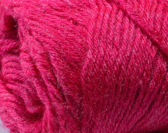 May include: Close-up of a vibrant fuchsia yarn ball. The yarn has a soft, textured appearance, with subtle silver threads interwoven throughout, adding a touch of shimmer. Ideal for knitting and crochet projects.
