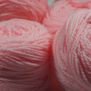 May include: Four balls of pink yarn, each wound into a tight coil.