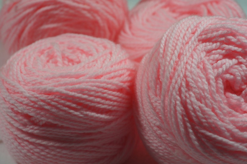 May include: Four balls of pink yarn, each wound into a tight coil.