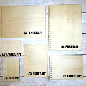 以下が含まれることがあります： さまざまなサイズと向きの木製ノートのコレクション。ノートは明るい色で、天然の木目があります。サイズにはA4、A5、A6が含まれ、横長と縦長のレイアウトがあります。テキストは各ノートのサイズと向きを示しています。