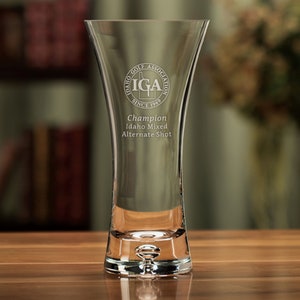 May include: A clear glass vase with a round base and a flared top. The vase is engraved with the text "Idaho Golf Association IGA Since 1969" and "Champion Idaho Mixed Alternate Shot".