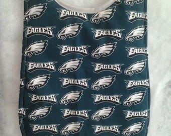 Puede incluir: Un babero de bebé verde con ribete blanco y un patrón repetido de logotipos blancos de los Philadelphia Eagles.