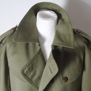 K&ouml;nnte beinhalten: Ein gr&uuml;ner Trenchcoat im Milit&auml;rstil mit doppelreihigem Verschluss und einem gro&szlig;en Kragen.