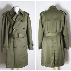 K&ouml;nnte beinhalten: Ein gr&uuml;ner, zweireihiger Trenchcoat mit G&uuml;rtel und braunen Kn&ouml;pfen.