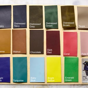 May include: A chart of 24 leather swatches in various colors, including black, navy, distressed navy, distressed grey, distressed green, distressed brown, taupe, bone, ginger, sienna, walnut, chocolate, dark red, coral, pale pink, pale purple, dark purple, bright blue, turquoise, baby blue, bright yellow, emerald green. The chart is labeled with the color names.