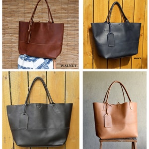 May include: Four leather tote bags in different colors: walnut, navy, black, and natural. Each bag has a single strap and a small leather tag.