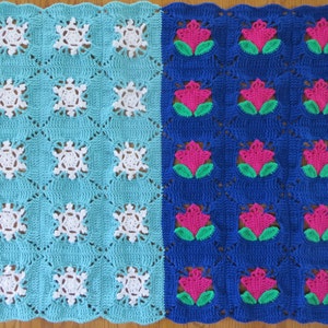 May include: A crocheted blanket with a blue and turquoise snowflake pattern on one side and a blue and pink flower pattern on the other side.