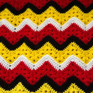 May include: A crocheted blanket with a chevron pattern in black, red, white and yellow.