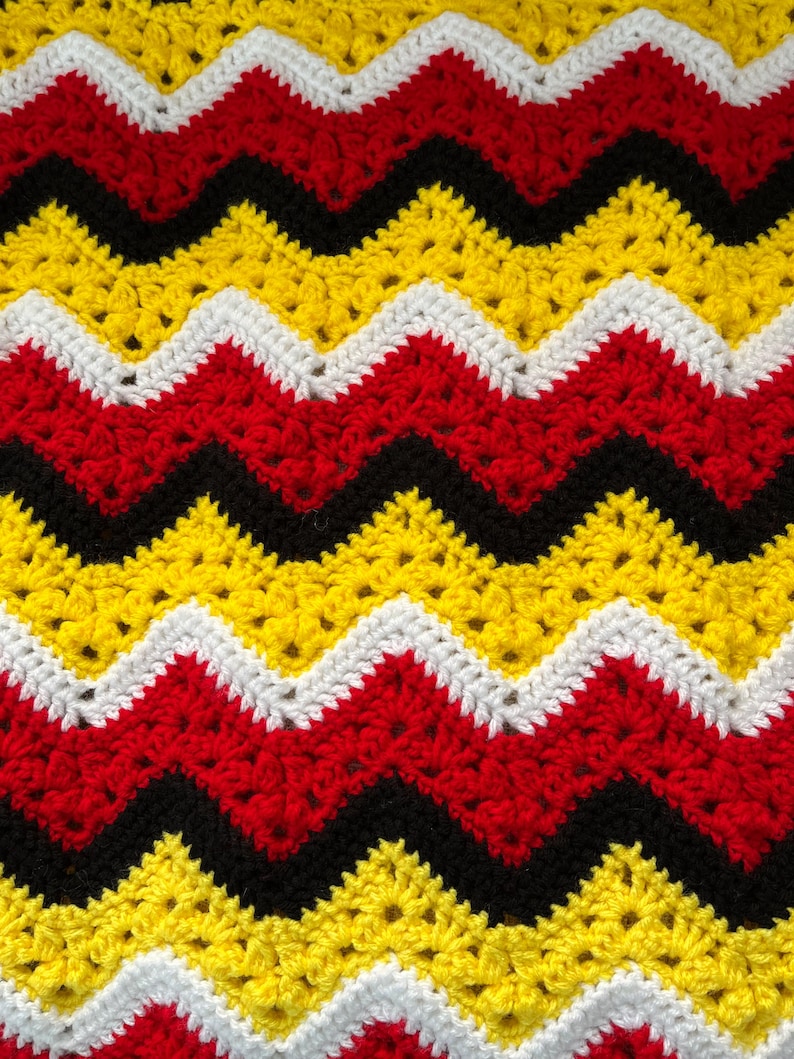 May include: A crocheted blanket with a chevron pattern in black, red, white and yellow.