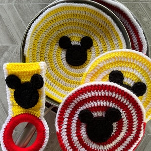 May include: Set of four crocheted pot holders featuring a Mickey Mouse design. The pot holders are in yellow, red, and white stripes with black Mickey Mouse ears and faces.