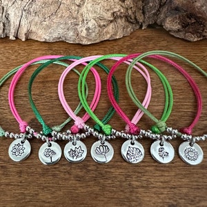 May include: Six colorful friendship bracelets with silver beads and charms featuring nature-inspired designs, including a flower, a leaf, a sunflower, and a fern.
