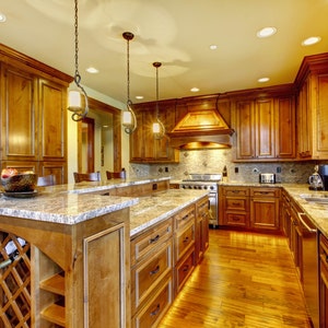 May include: A kitchen with wood cabinets, granite countertops, and stainless steel appliances. The kitchen features a large island with a wine rack and a breakfast bar.