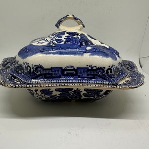 May include: A blue and white porcelain serving dish with a lid. The dish features a traditional Chinese willow pattern.
