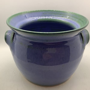 May include: A blue ceramic pot with two handles. The pot has a green glaze around the rim.