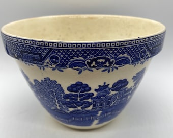 May include: A white ceramic mixing bowl with a blue and white willow pattern. The bowl has a scalloped rim and a wide base.